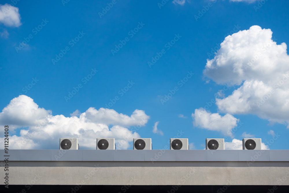 Several fans of an air conditioning system on the roof of a building against a blue sky background. The photo was taken on a sunny day.