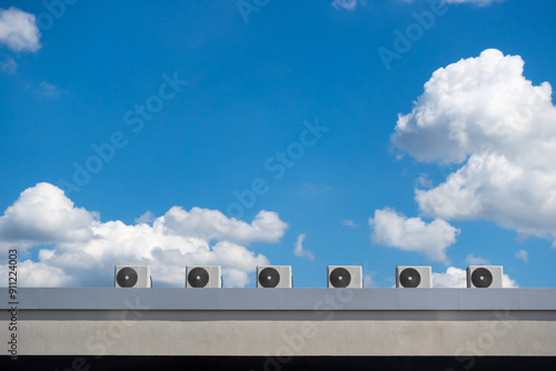 Several fans of an air conditioning system on the roof of a building against a blue sky background. The photo was taken on a sunny day.