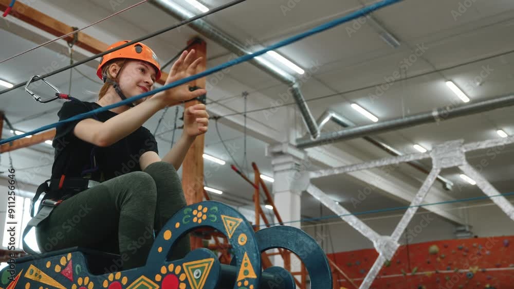 A cute 14-year-old girl trains in a rope park during school holidays. A strong girl wearing an orange protective helmet rides a cart using a winch or zip line. High quality 4k footage A cute 14-year-old girl trains in a rope park during school holidays. A strong girl wearing an orange protective helmet rides a cart using a winch or zip line. High quality 4k footage