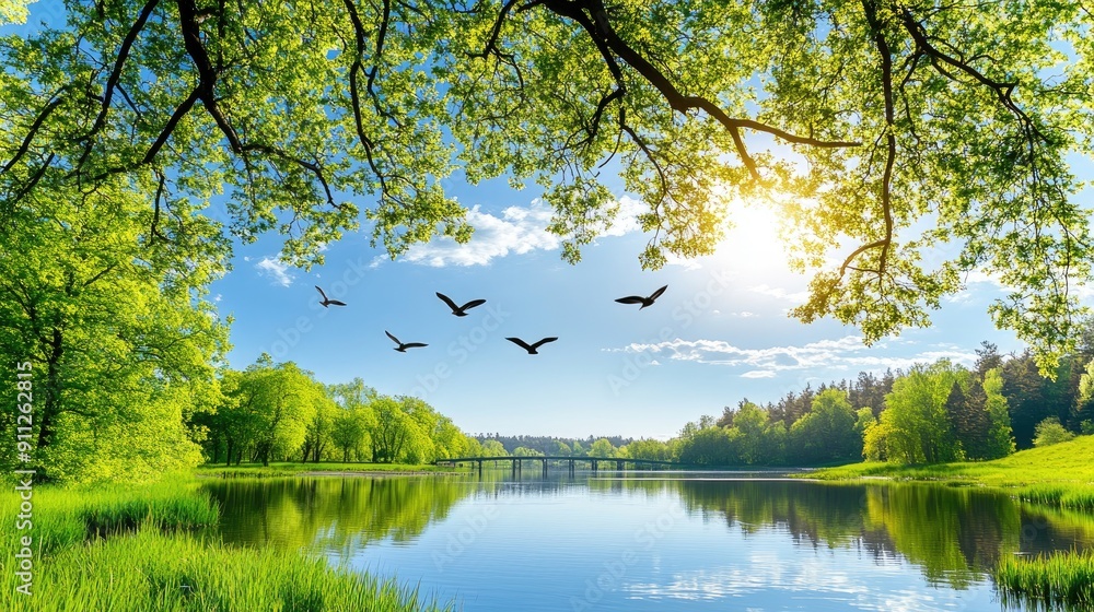 Obraz premium A tranquil lake reflects the vibrant green landscape and blue sky, with birds soaring above, creating a peaceful morning atmosphere in nature