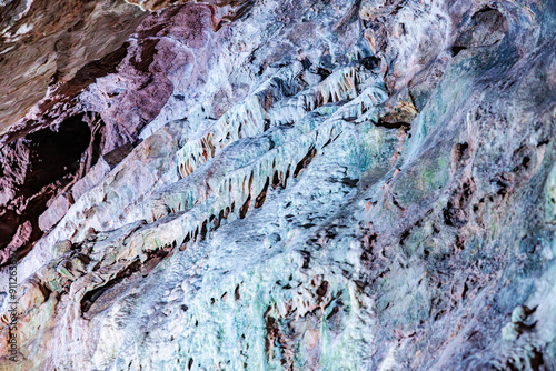 Rock walls with minerals from water seepage in Neptune's caves, underground rock formation illuminated with artificial light, cracked, rough and uneven walls, Couvin, Wallonia, Belgium photo