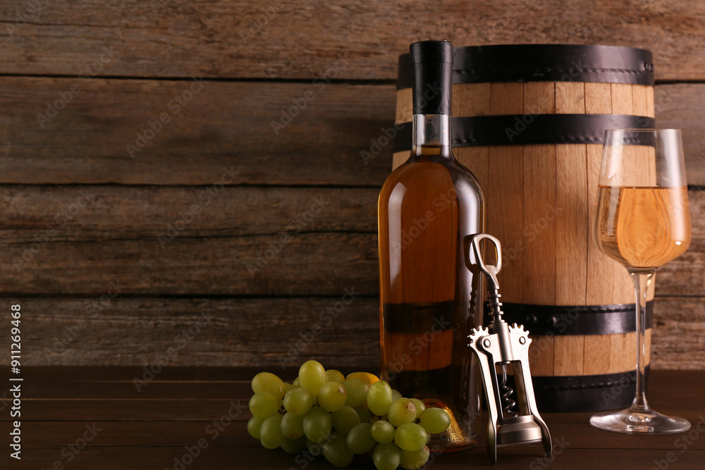 Obraz premium Glass of wine, bottle, wing corkscrew, barrel and grapes on wooden table, space for text