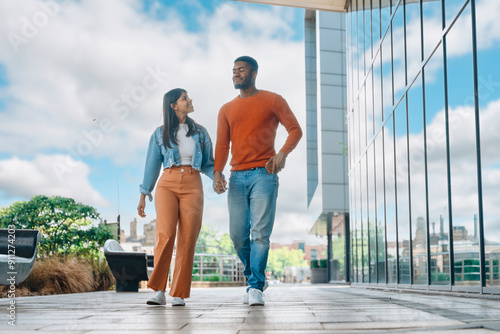 Young Couple Strolling Hand in Hand Near Modern Architecture on Bright Sunny Day