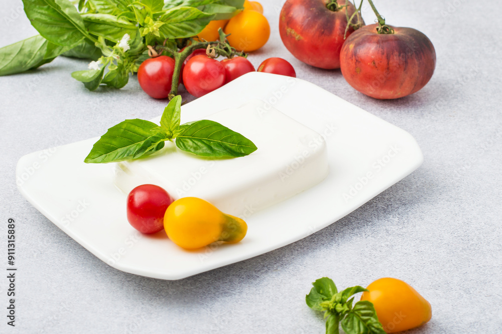 Feta on a plate with basil, yellow and red tomatoes. Horizontal. Feta on a plate with basil, yellow and red tomatoes. Horizontal.