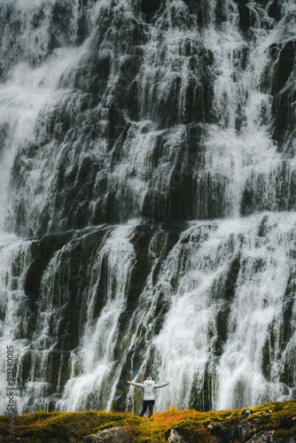 Small hiker in front of the massive Dynjandi waterfall, in the Westfjords of Iceland