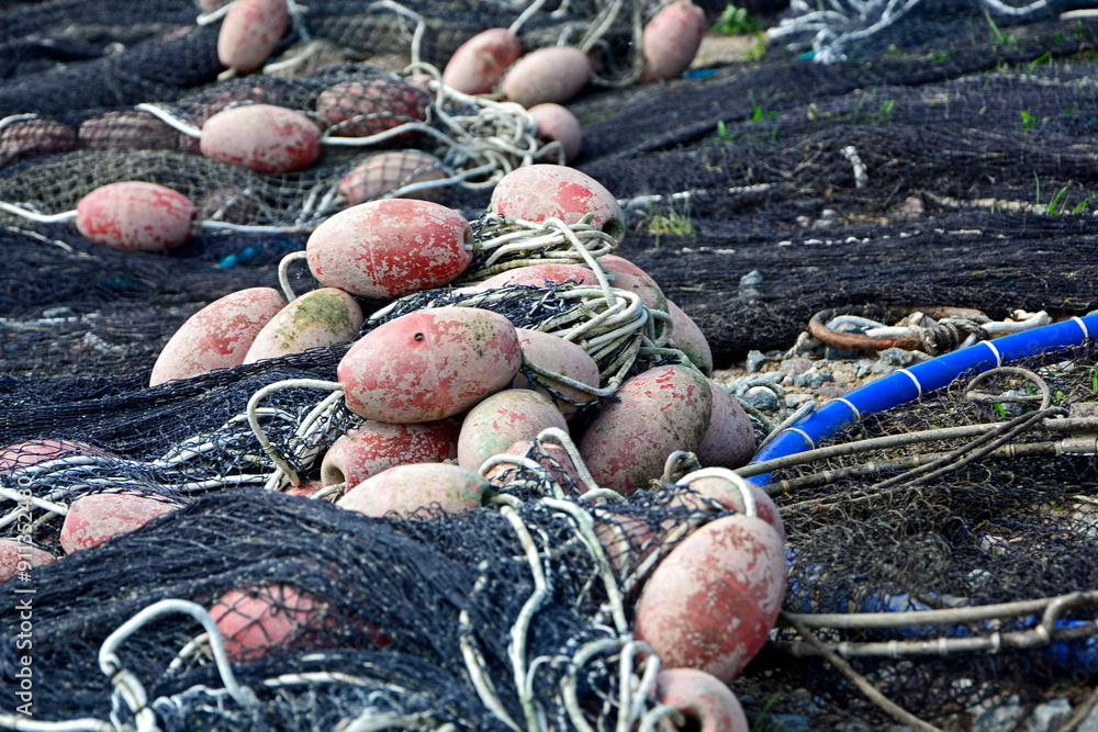 sieć rybacka z pływakami na brzegu, suszące sie na brzegu sieci rybackie z pływakami, fishing net on the shore, fishing net drying, Fishing net in the harbor, nets and floats are dried on the shore.