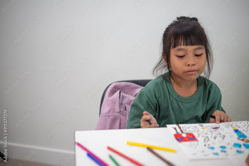 A young girl is sitting at a table with a pencil and a piece of paper in her hand. She is practicing drawing and coloring, honing her skills at home. A young girl is sitting at a table with a pencil and a piece of paper in her hand. She is practicing drawing and coloring, honing her skills at home.