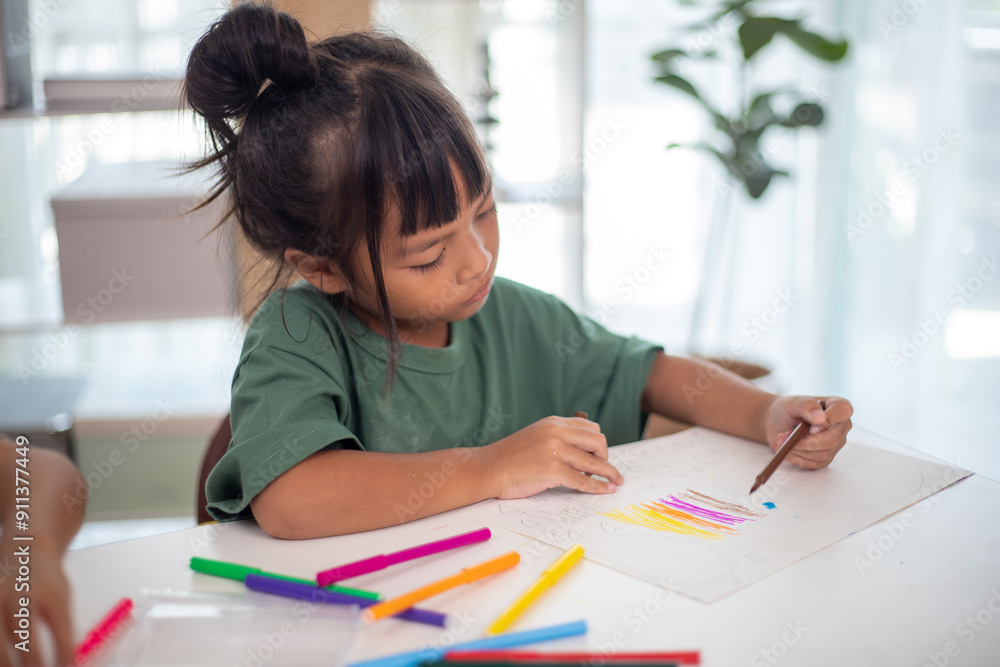 A young girl is sitting at a table with a pencil and a piece of paper in her hand. She is practicing drawing and coloring, honing her skills at home. A young girl is sitting at a table with a pencil and a piece of paper in her hand. She is practicing drawing and coloring, honing her skills at home.