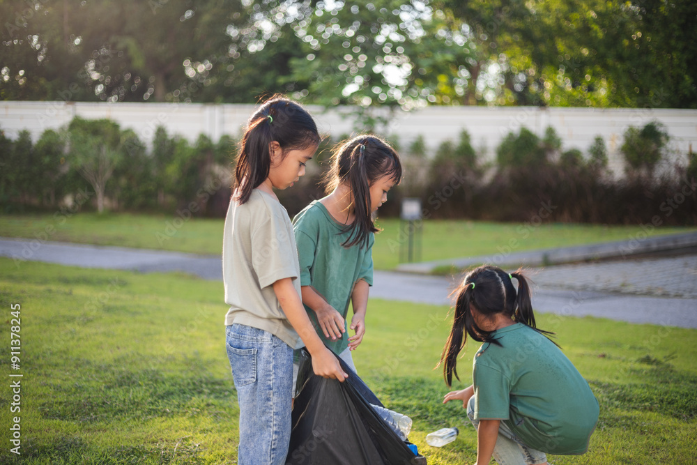 Three young girls are picking up trash in a park