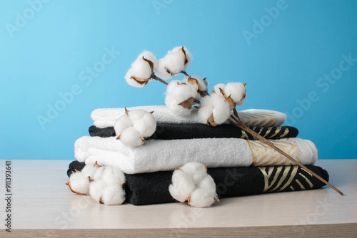 Canvas Print Stack of Black and White Towels with Cotton Branch Against Light Blue Background