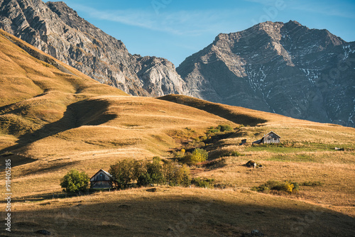 Wooden hut on brown hill grassland and rocky mountain in rural scene