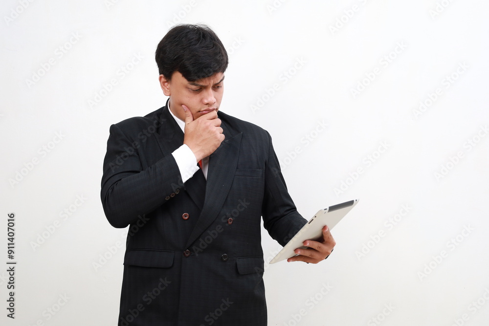 Confused Shocked asian office worker in suit looking worried at tablet computer screen, having trouble at work, standing on white background. Confused Shocked asian office worker in suit looking worried at tablet computer screen, having trouble at work, standing on white background.