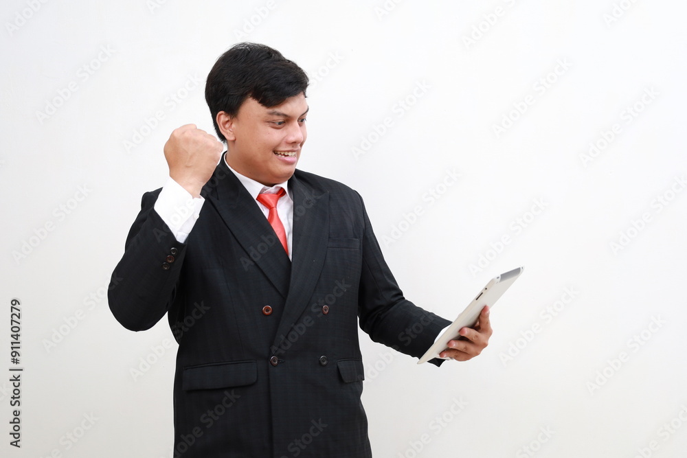 Young asian businessman wearing a suit posing holding tablet computer with fist hand, isolated on a white background Young asian businessman wearing a suit posing holding tablet computer with fist hand, isolated on a white background