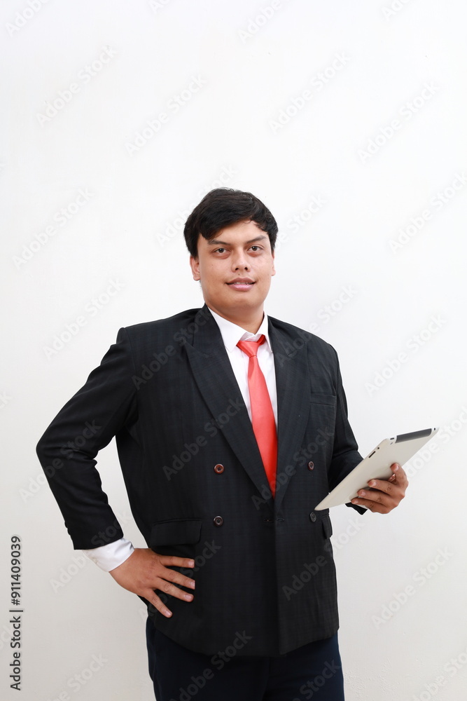 Portrait of a young Asian male businessman in formal suit standing holding tablet computer. Isolated in white background Portrait of a young Asian male businessman in formal suit standing holding tablet computer. Isolated in white background