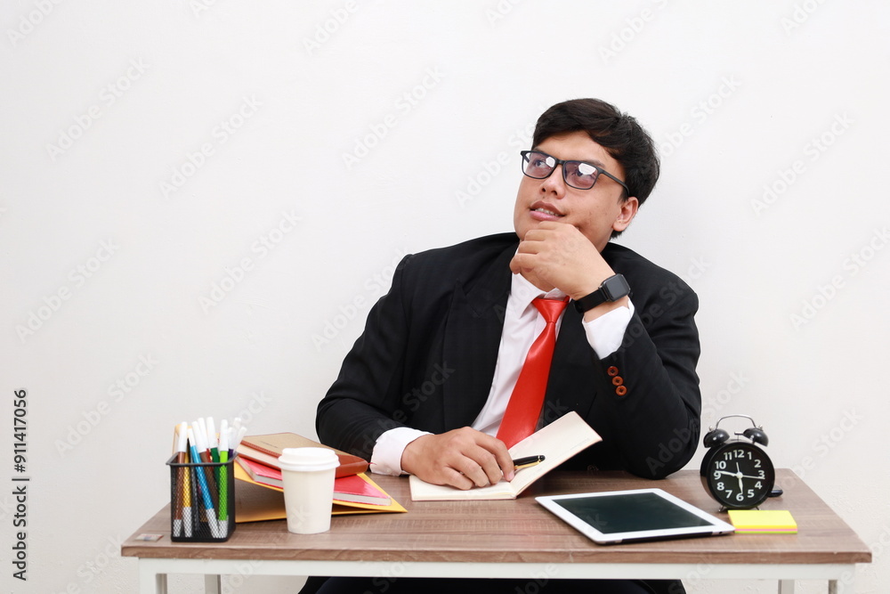 Handsome businessman thinking while working on computer at office
