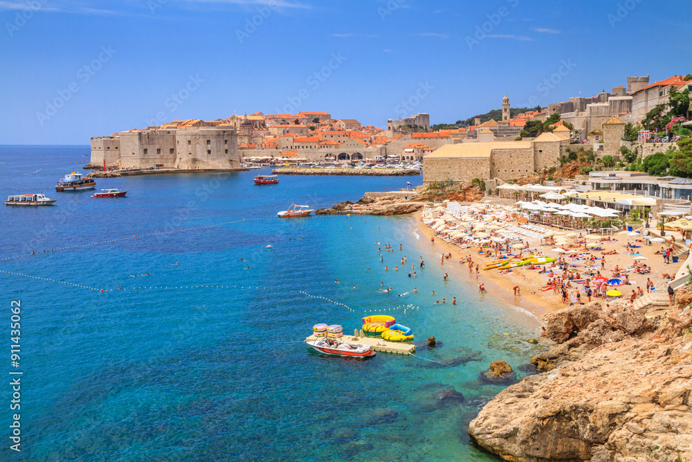 Coastal summer landscape - view of the city beach on the background of the Old Town of Dubrovnik on the Adriatic coast of Croatia Coastal summer landscape - view of the city beach on the background of the Old Town of Dubrovnik on the Adriatic coast of Croatia