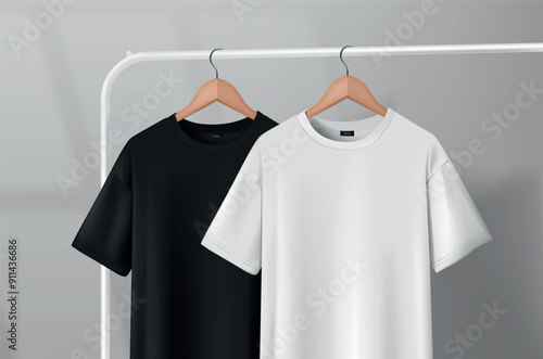 Black and white t-shirts hanging on a clothes rack in a studio on a wooden hanger.