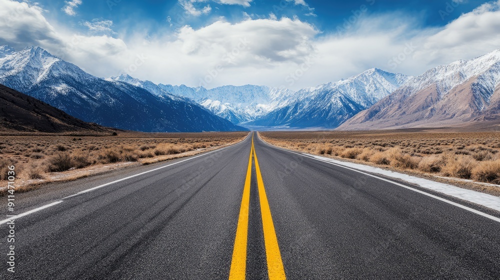 Naklejka premium Long, straight road through snow mountains under a dramatic sky, capturing the essence of adventure.