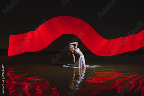 Obraz na płótnie Young slim girl in white swimsuit posing in water at night with abstract red light effect w salonie
