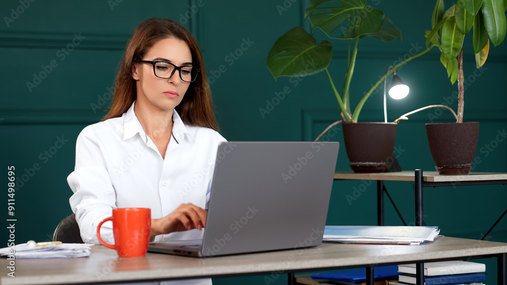 Perfect for concepts of productivity, business, and contemporary work environment. Stylish young woman working on a laptop in a modern office. Perfect for concepts of productivity, business, and contemporary work environment. Stylish young woman working on a laptop in a modern office.