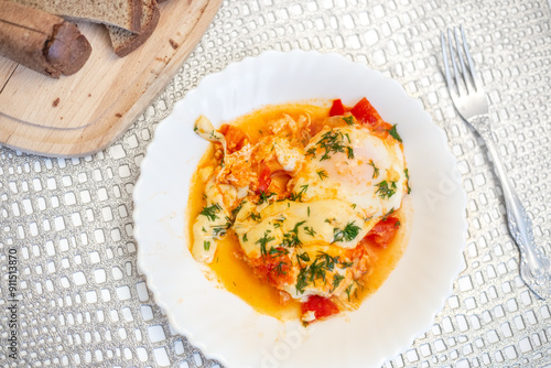 Israeli dish Shakshuka. Eggs with tomatoes on a white plate