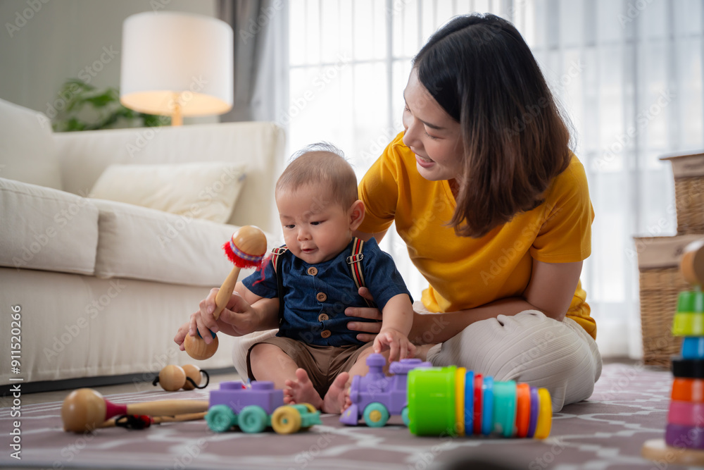 A woman is playing with a baby on the floor. The baby is holding a blue and purple toy A woman is playing with a baby on the floor. The baby is holding a blue and purple toy