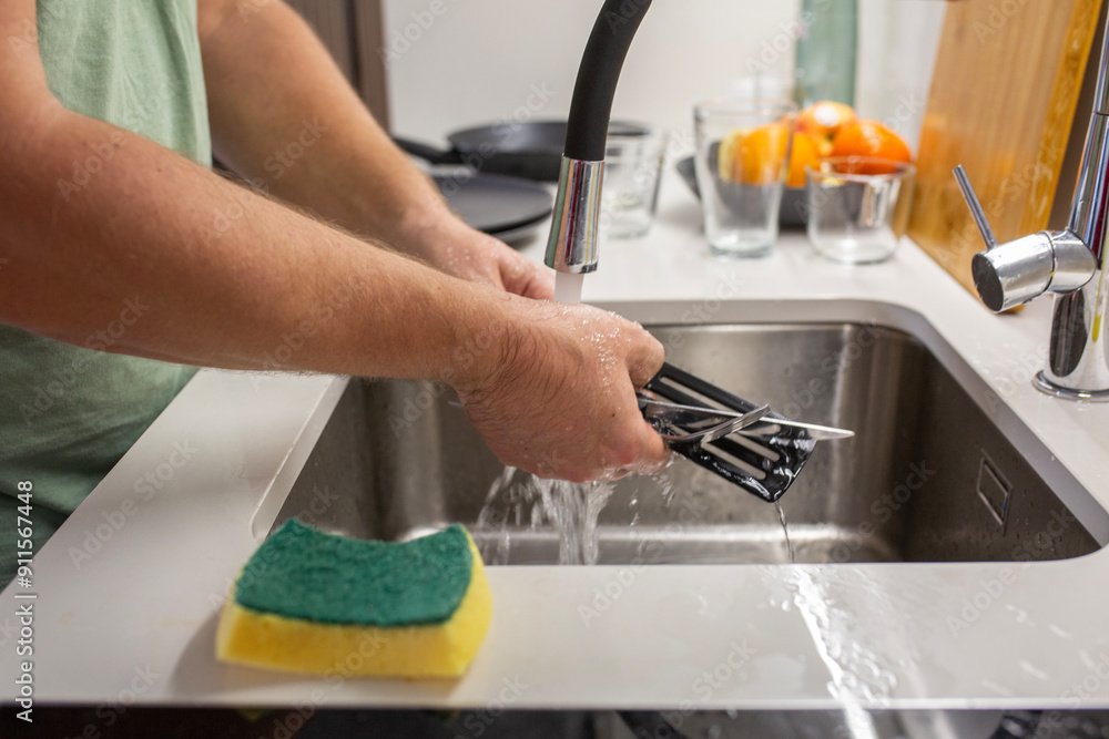 housekeeper Man Washing The Dishes on minimalistic kitchen. housekeeper Man Washing The Dishes on minimalistic kitchen.