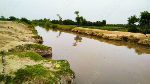 Water channel irrigation system, canal branch to irrigate agricultural land in the countryside, tranquil waters by a rural path image stock photo  photo