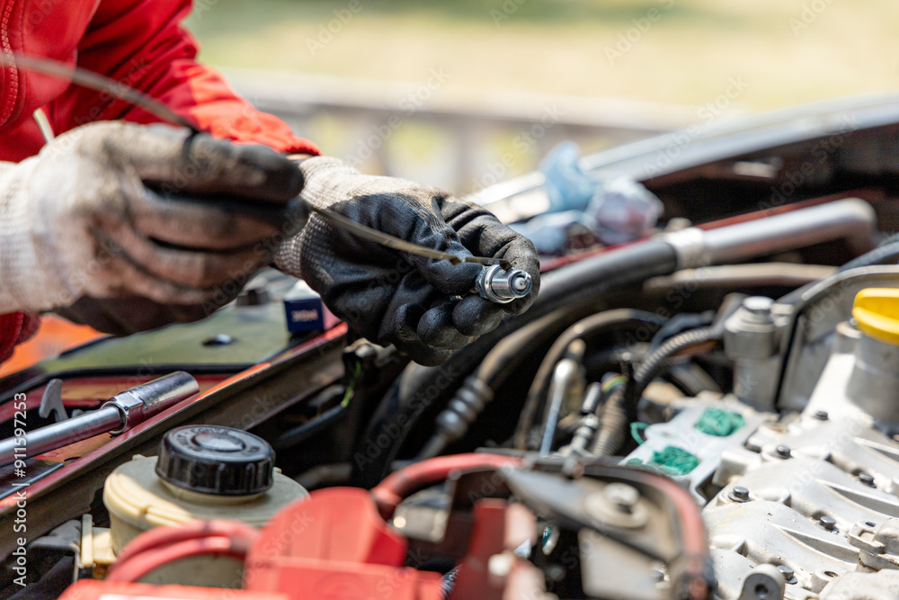 Close-up of the hands of a mechanic oiling a new spark plug Close-up of the hands of a mechanic oiling a new spark plug