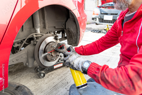 An auto mechanic employs a degreaser to clean the car's brake discs photo