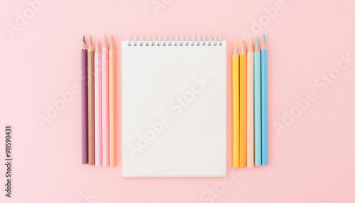 Blank notepad on pink pastel colored background surrounded by colored pencils business resource