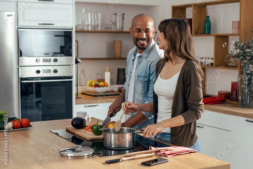 Happy beautiful couple cooking together in the kitchen at home