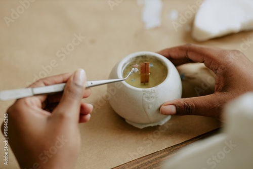 Hands skillfully crafting handmade candle. Person holding a tool, working on intricate details with focus and precision, showcasing artistry in candle making photo