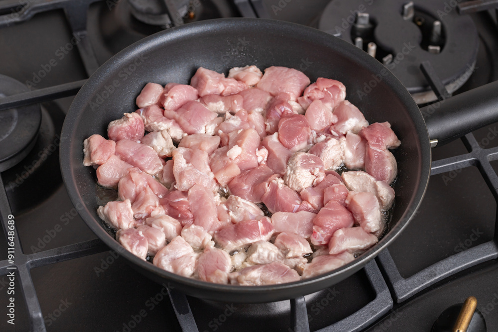 Sliced small pieces of raw meat are fried in a frying pan. Roasting beef or pork in a pan. Sliced small pieces of raw meat are fried in a frying pan. Roasting beef or pork in a pan.