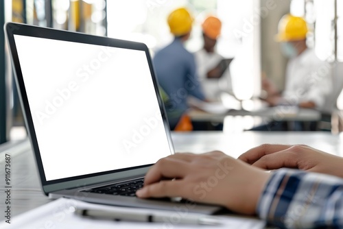 close up of an open laptop with a blank screen, set on a table in front of or behind three people