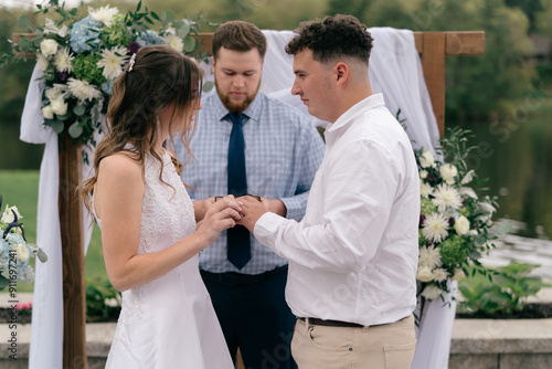 bride and groom exchanging rings during wedding ceremony photo