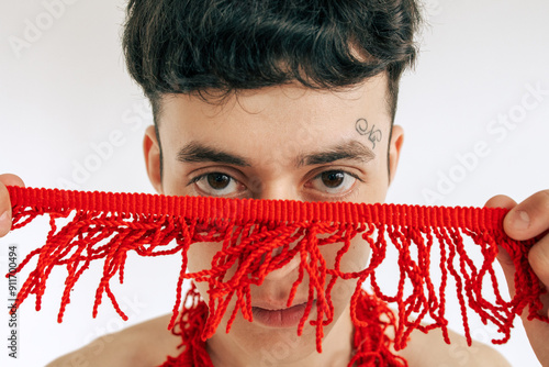 A man holds a red woven fringe in his hands
