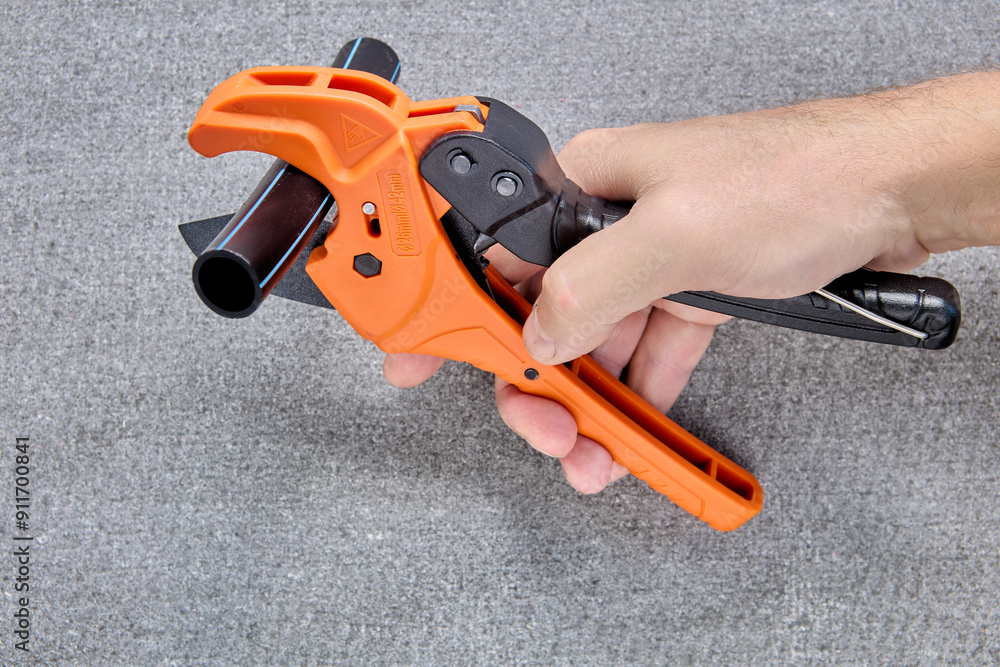 Cutting plastic pipes with cutter in form of scissors, gray background, close up. Cutting plastic pipes with cutter in form of scissors, gray background, close up.