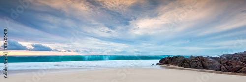 Dramatic skies and large wave curl on sandy beach