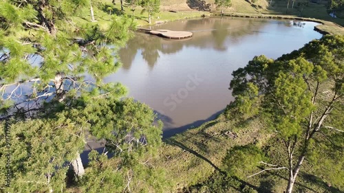 Por cima de um lago com um deck pier em formato de violão em meio a natureza em uma cidade do interior.