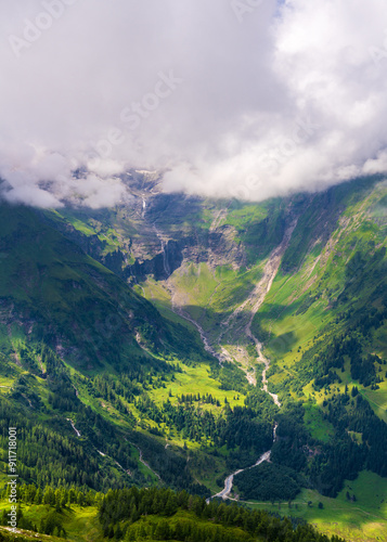 Majestic mountain peaks covered with clouds. Mountain rivers, waterfalls quickly flow down. The famous high mountain road Grossglocknerstrasse. Austria. Hohe Tauern Park. photo