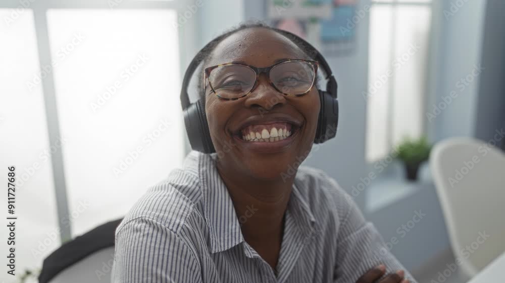 Woman smiling wearing headphones and glasses in an office setting, displaying joy and engagement in a professional environment. Woman smiling wearing headphones and glasses in an office setting, displaying joy and engagement in a professional environment.