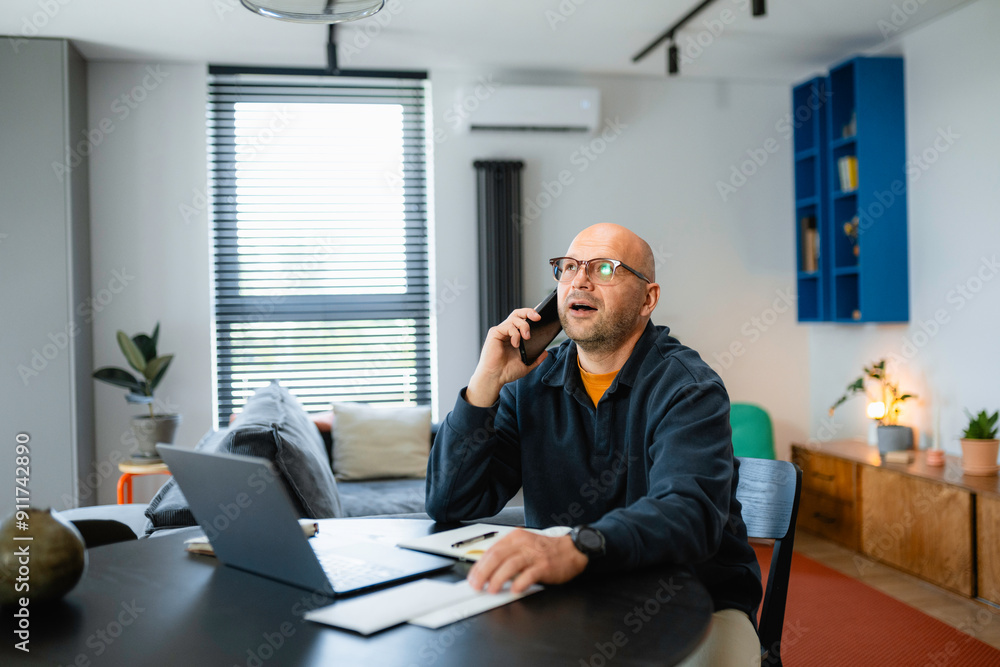 A man is talking on a mobile phone and using a laptop A man is talking on a mobile phone and using a laptop