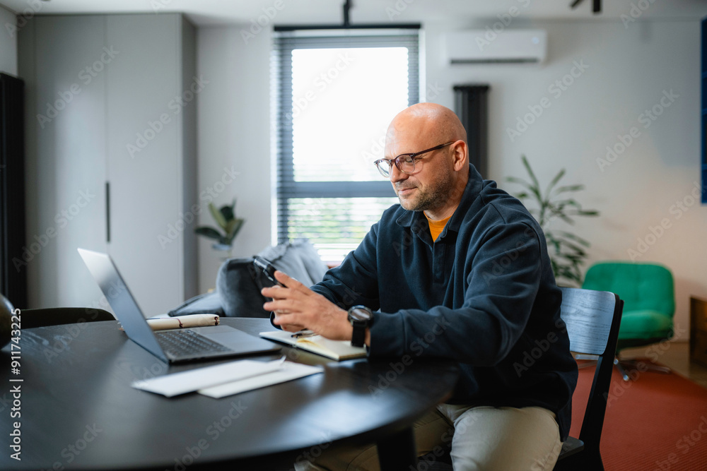 A man uses a mobile phone sitting at his desk A man uses a mobile phone sitting at his desk