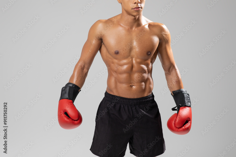 A fit young man boxer stands confidently in a studio, showcasing his defined abs and muscular arms while wearing vibrant red boxing gloves, cropped A fit young man boxer stands confidently in a studio, showcasing his defined abs and muscular arms while wearing vibrant red boxing gloves, cropped