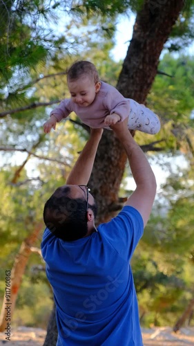 A father lifting his baby girl up to the sky, making her smile with joy and sharing a wonderful moment together
