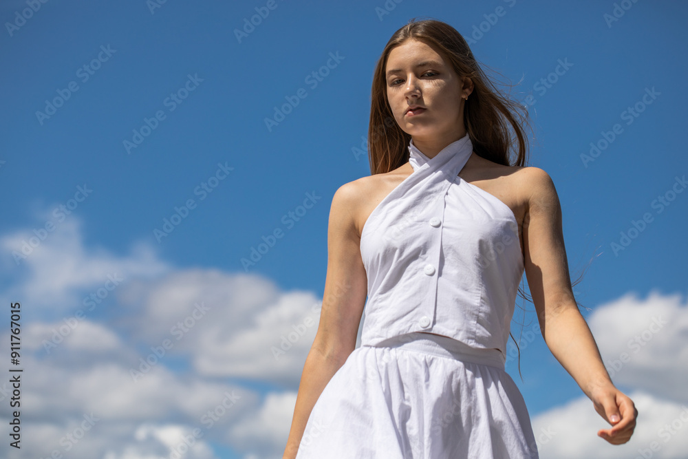 Young beautiful girl in a summer dress walking along the embankment