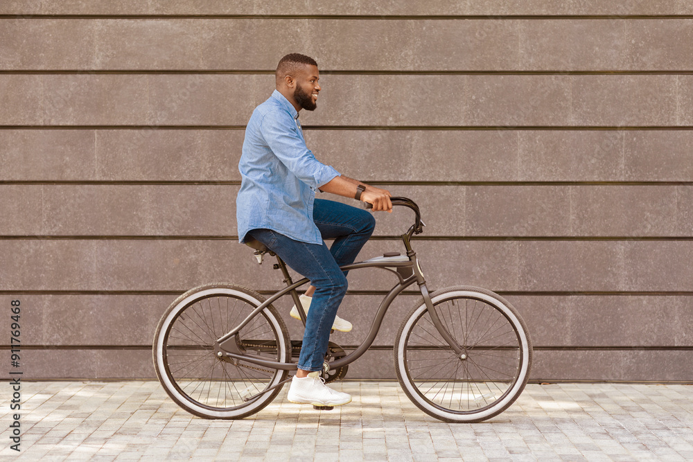 Way to office. Young african american businessman riding bicycle against urban wall background, going to work Way to office. Young african american businessman riding bicycle against urban wall background, going to work