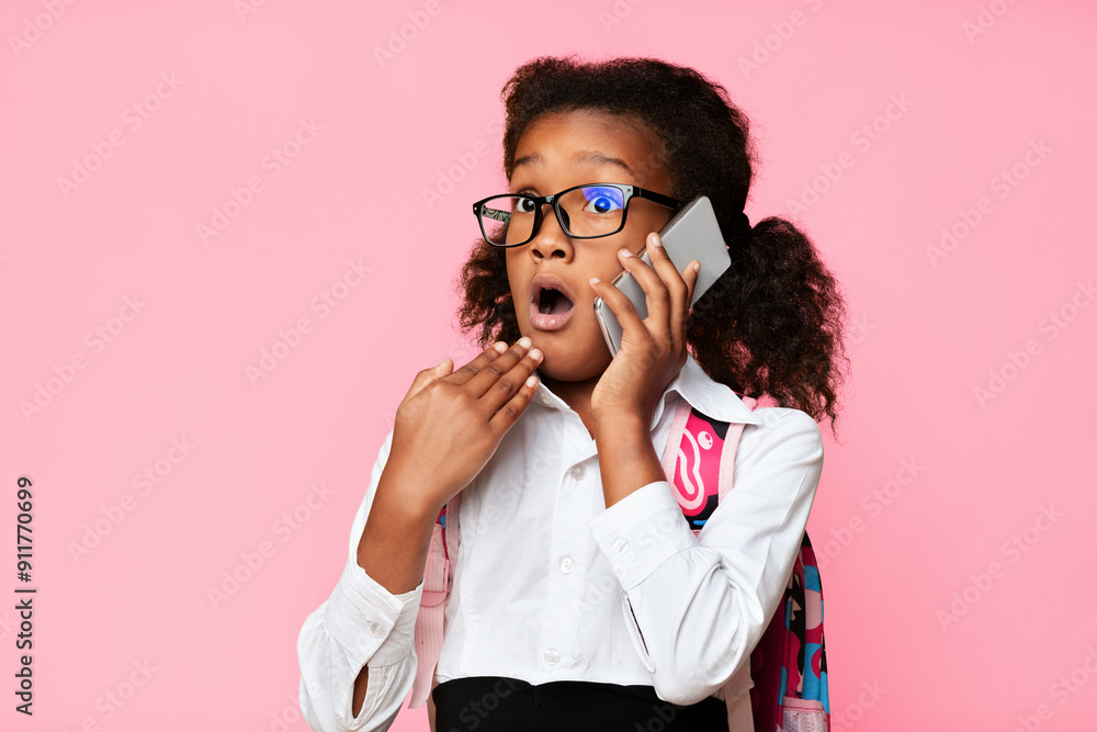 OMG, School News. Surprised Afro Schoolgirl Talking On Phone Over Yellow Studio Background. Free Space OMG, School News. Surprised Afro Schoolgirl Talking On Phone Over Yellow Studio Background. Free Space