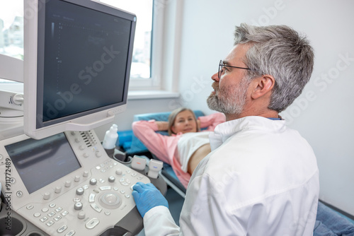 Gray-haired male doctor working with patient and making ultrasonography